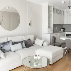 Okrągłe lustra w salonie nowoczesnym dodają elegancji. Jasna kanapa, kuchnia i jadalnia tworzą spójną całość.