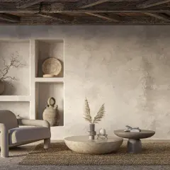Wnętrze w stylu boho z fotelem, okrągłym stolikiem i dekoracjami. Ściany imitują tynk wapienny, pokazując, jak malować wapnem dla uzyskania naturalnego efektu.