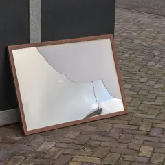 Zepsute lustro w drewnianej ramie leży na bruku. Czy lustro można wyrzucić do szkła?