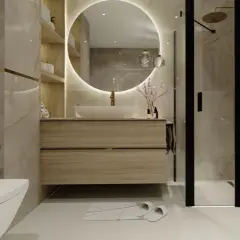 Elegancka łazienka z podświetlanym lustrem, nad którym znajduje się lampa nad lustro na baterie. Obok prysznic i toaleta.