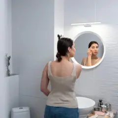 Kobieta wykonuje poranny rytuał pielęgnacyjny przed lustrem z oświetleniem led.