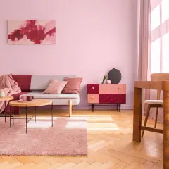 Przytulny salon z sofą, stolikami kawowymi i dywanem w odcieniach brudnego różu. Ściany w tym samym kolorze tworzą ciepłą atmosferę.