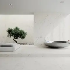 Nowoczesna łazienka z wanną i łóżkiem, gdzie króluje biały marmur. W tle drzewko bonsai.