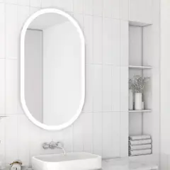 Owalne lustro z podświetleniem to idealne rozwiązanie, jakie lustro do małej łazienki. Minimalistyczny design, białe płytki i subtelne dodatki tworzą jasną przestrzeń.