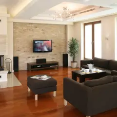 Przytulny salon w beżach i brązach z kominkiem, ceglaną ścianą i wygodnymi sofami.