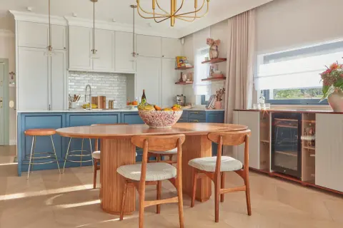 Jadalnia w stylu mid century modern z owalnym drewnianym stołem, krzesłami i wyspą kuchenną.