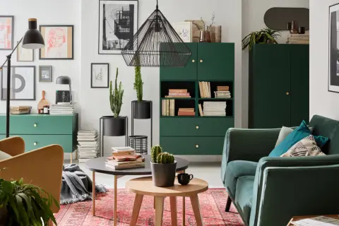 Zielony salon inspiracje: stylowe meble, kaktusy i sztuka na ścianach tworzą przytulną atmosferę.