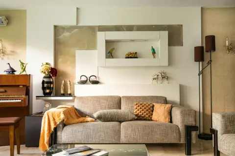 Beżowy salon aranżacje: sofa, fortepian, dekoracje, lampy. Ciepłe kolory i eleganckie dodatki tworzą przytulną atmosferę.
