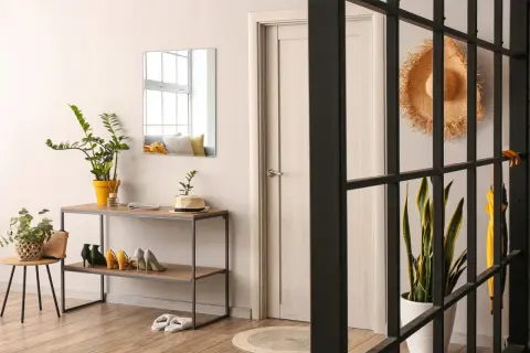 Eleganckie lustro fazowane do przedpokoju nad konsolą z butami i roślinami.