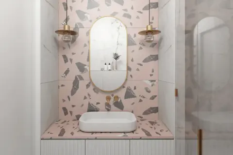 Eleganckie lustra owalne do łazienki z złotą ramą, wiszące nad umywalką, w otoczeniu różowych i szarych płytek terrazzo.
