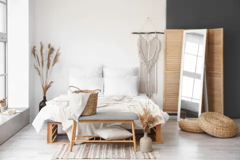 Białe lustro stojące odbija okno, dodając lekkości sypialni w stylu boho.