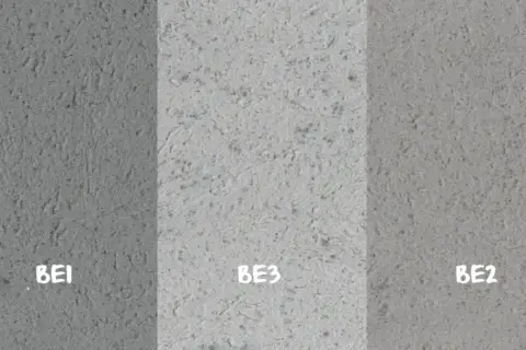 Próbki betonu dekoracyjnego na ścianę: BE1 (ciemniejszy), BE3 (jasny), BE2 (średni). Różne tekstury i odcienie szarości.