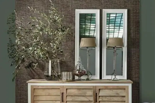 Dwa wąskie lustra do przedpokoju w białych ramach, odbijające światło i tworzące przestrzeń. Obok stoją lampy i wazon z gałązkami.