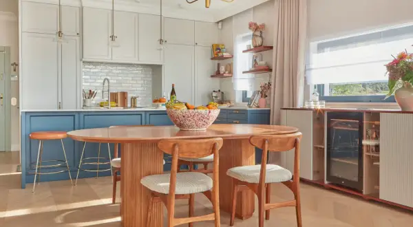 Jadalnia w stylu mid century modern z owalnym drewnianym stołem, krzesłami i wyspą kuchenną.
