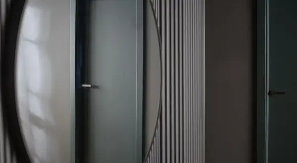 Okrągłe lustro na przedpokój odbija drzwi w stonowanym kolorze.
