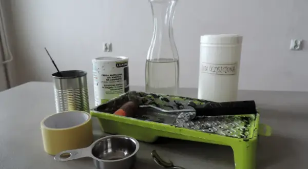 Przygotowania do malowania farbą tablicową: puszka farby, soda oczyszczona, wałek, kuweta, taśma, miarka i łyżeczka.
