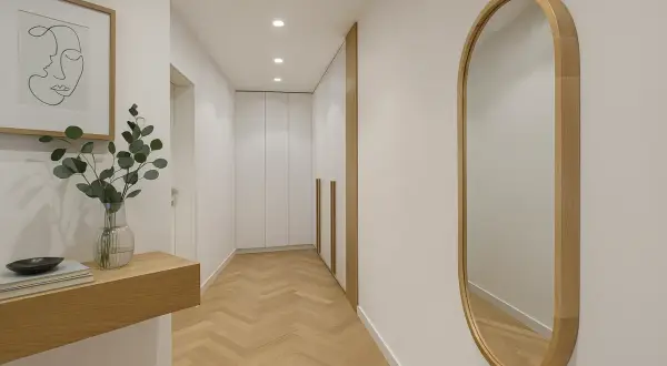 Eleganckie lustro owalne w drewnianej ramie odbija światło w nowoczesnym korytarzu z parkietem w jodełkę.
