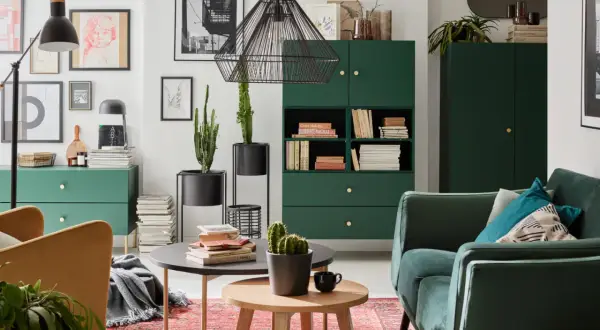 Zielony salon inspiracje: stylowe meble, kaktusy i sztuka na ścianach tworzą przytulną atmosferę.