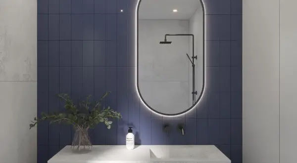 Eleganckie lustro z podświetleniem do łazienki nad kamiennym blatem z umywalką i roślinami.