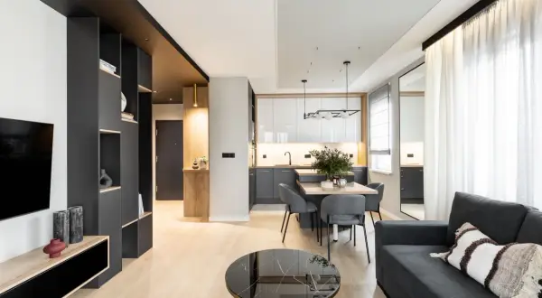 Nowoczesne salon aranżacje: szara sofa, czarna zabudowa, drewniane akcenty i minimalistyczna kuchnia tworzą spójną całość.