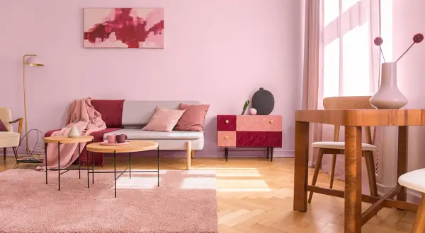 Salon w odcieniach brudny róż kolor. Sofa, dywan i zasłony tworzą przytulną atmosferę.