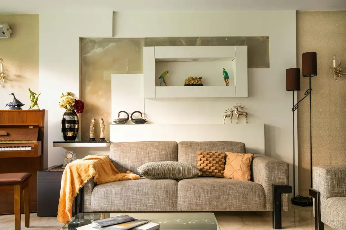 Beżowy salon aranżacje: sofa, fortepian, dekoracje, lampy. Ciepłe kolory i eleganckie dodatki tworzą przytulną atmosferę.