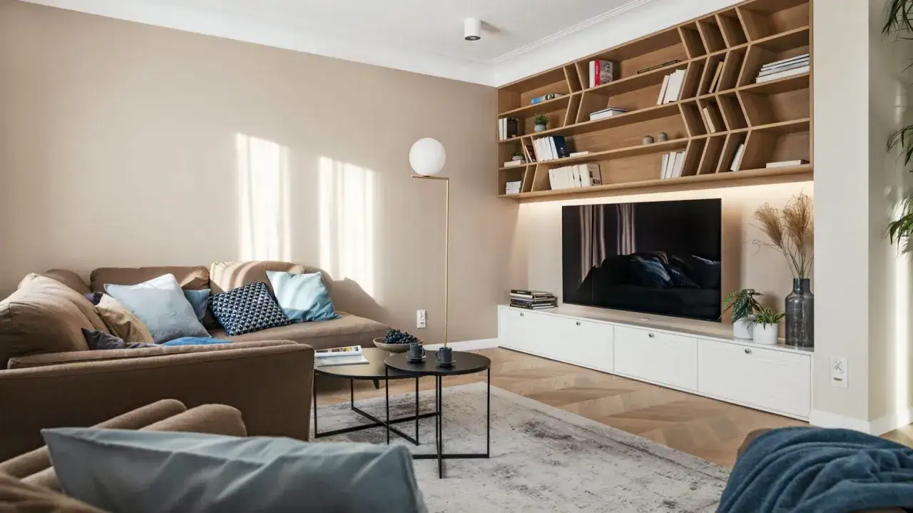 Przytulny salon w beżach i brązach. Miękka kanapa, drewniana biblioteczka i nowoczesny stolik kawowy tworzą ciepłą atmosferę.