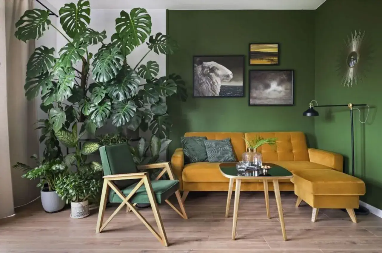 Zielony pokój inspiracje: bujna monstera, musztardowa kanapa i fotel tworzą przytulną przestrzeń.