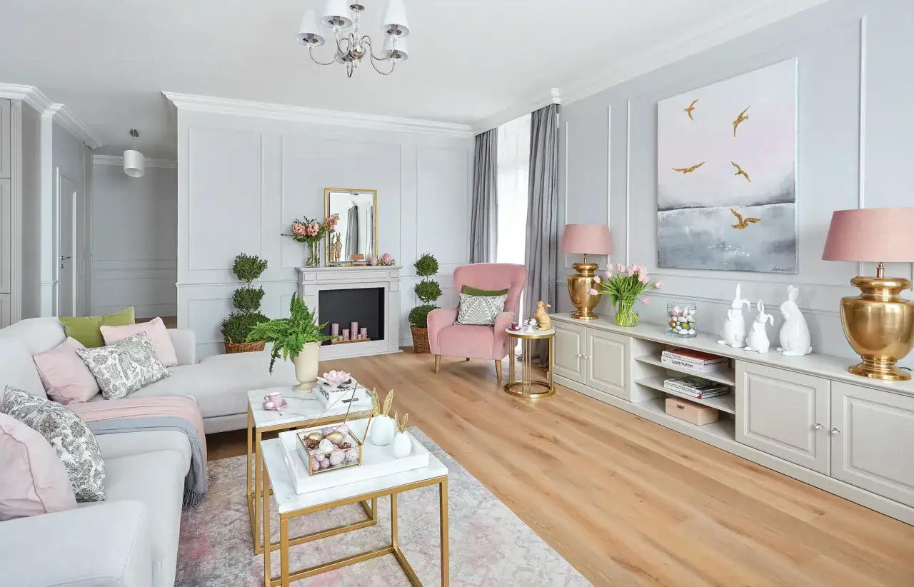 Przytulny salon z sofą i fotelem w kolorze pudrowego różu. Ściany w odcieniach szarości i pudrowego różu tworzą harmonijną całość.