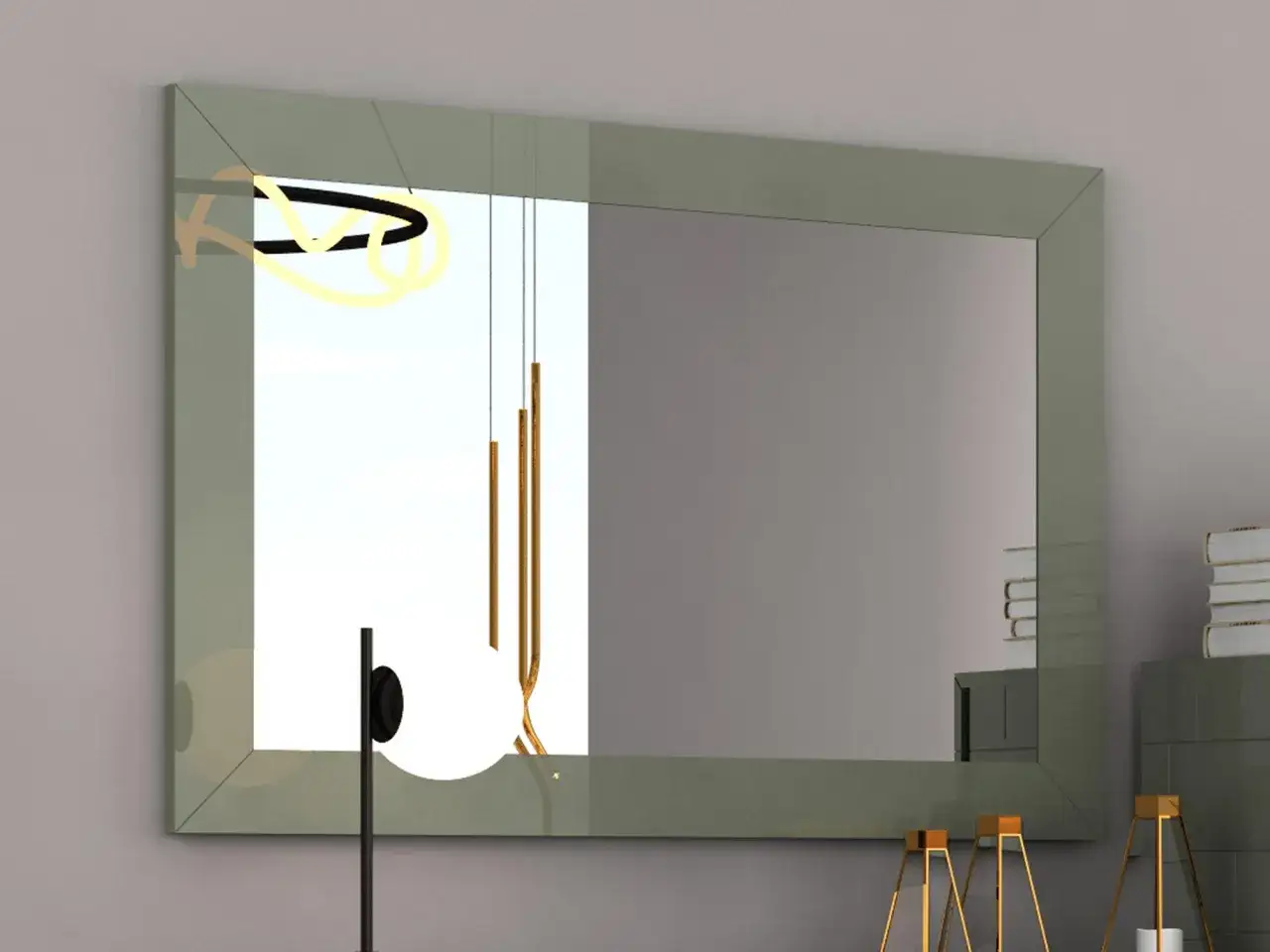 Eleganckie, lustro wąskie długie w zielonej ramie odbija nowoczesne lampy i stos książek.