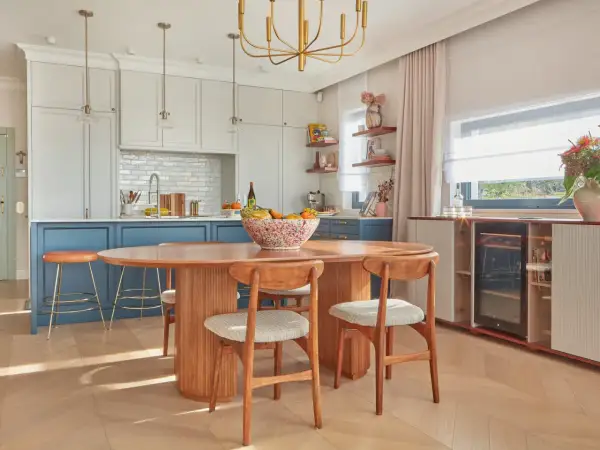 Jadalnia w stylu mid century modern z owalnym drewnianym stołem, krzesłami i wyspą kuchenną.