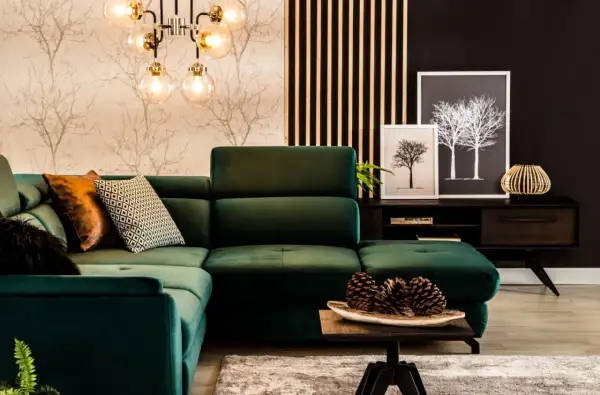 Wygodna, ciemno zielona kanapa w salonie z ozdobnymi poduszkami i lampą w stylu retro.