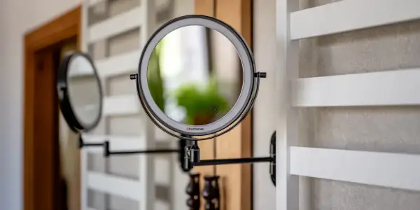 Eleganckie, czarne lustro łazienkowe z podświetleniem LED, zamontowane na wysięgniku. Obok widać drugie lustro.