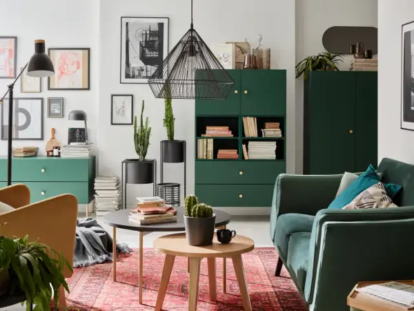 Zielony salon inspiracje: stylowe meble, kaktusy i sztuka na ścianach tworzą przytulną atmosferę.