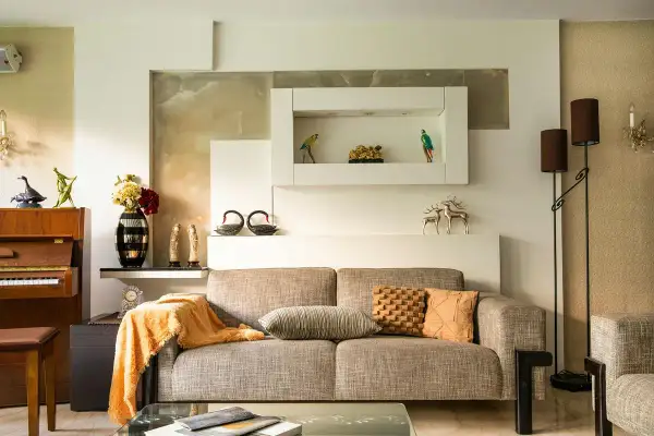 Beżowy salon aranżacje: sofa, fortepian, dekoracje, lampy. Ciepłe kolory i eleganckie dodatki tworzą przytulną atmosferę.