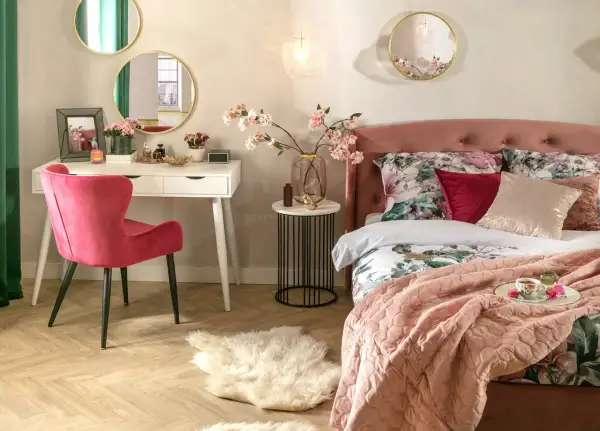 Elegancka toaletka w sypialni aranżacje: biała toaletka, różowe krzesło, lustra i kwiaty tworzą przytulną przestrzeń.