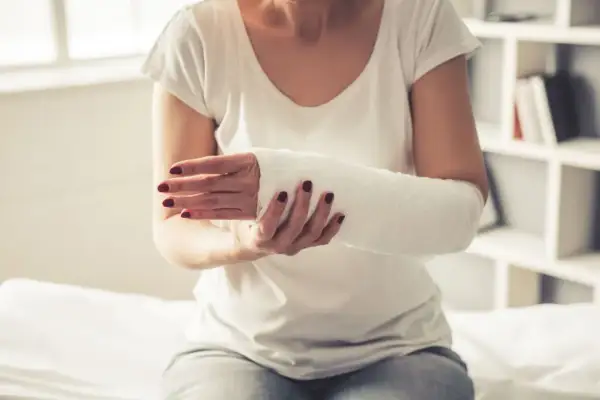 Kobieta z ręką w gipsie, zastanawia się, co zrobić, żeby gips szybko nie stwardniał.